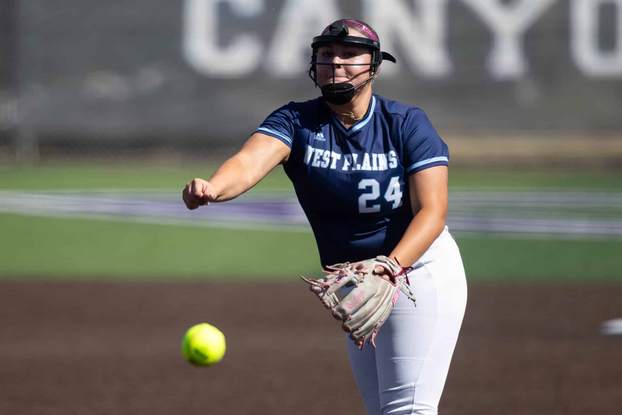 Softball pitcher in navy West Plains jersey #24 delivering a pitch on the field.