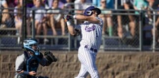 Baseball batter in white pinstripe uniform swinging at a pitch, catcher crouched behind him.