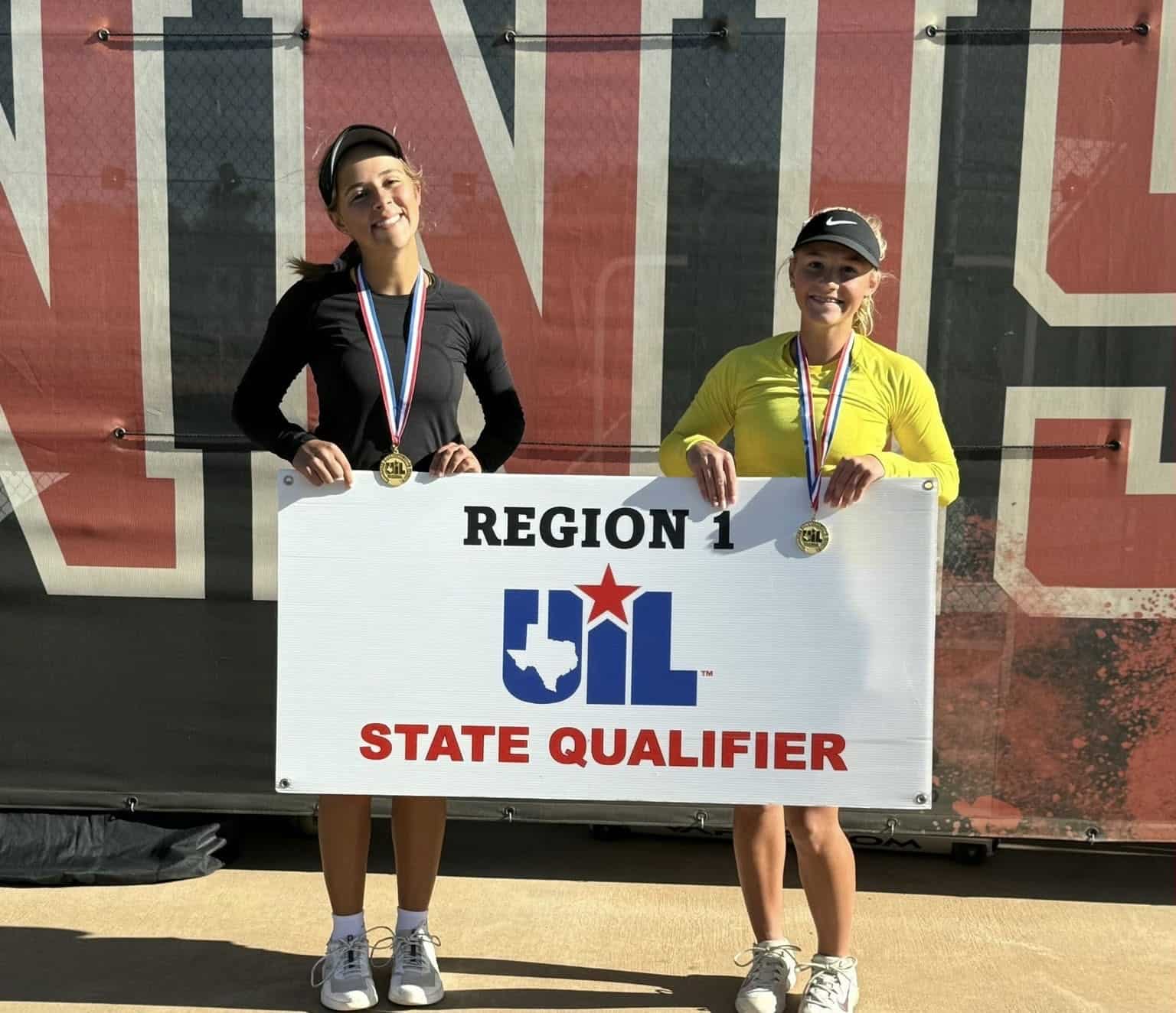 Two young female runners pose with gold medals, holding a banner that reads REGION 1 STATE QUALIFIER.