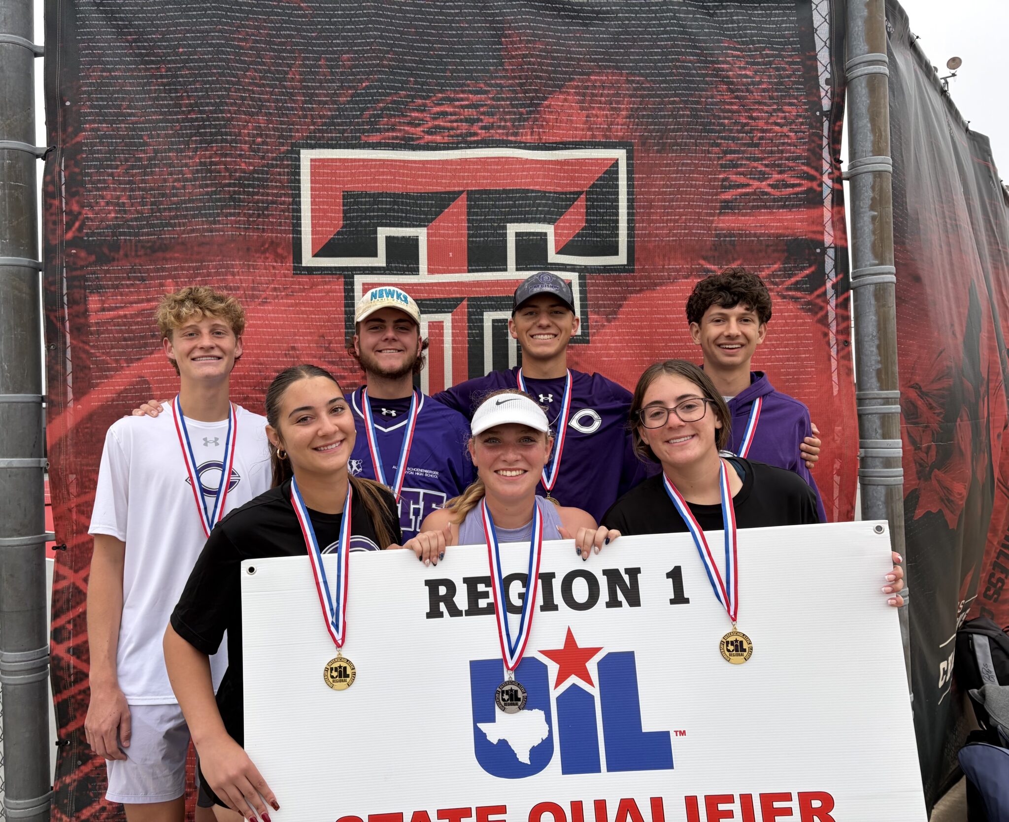 Group of smiling students with medals posing in front of a banner reading REGION 1 and a blue star logo behind them.