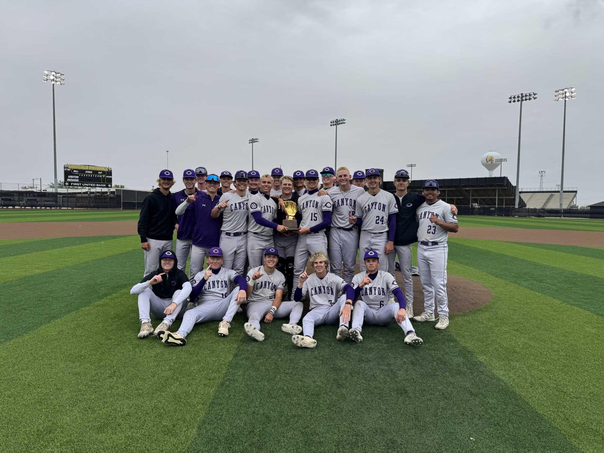 Canyon high school baseball team posing with a trophy on the field after a game.