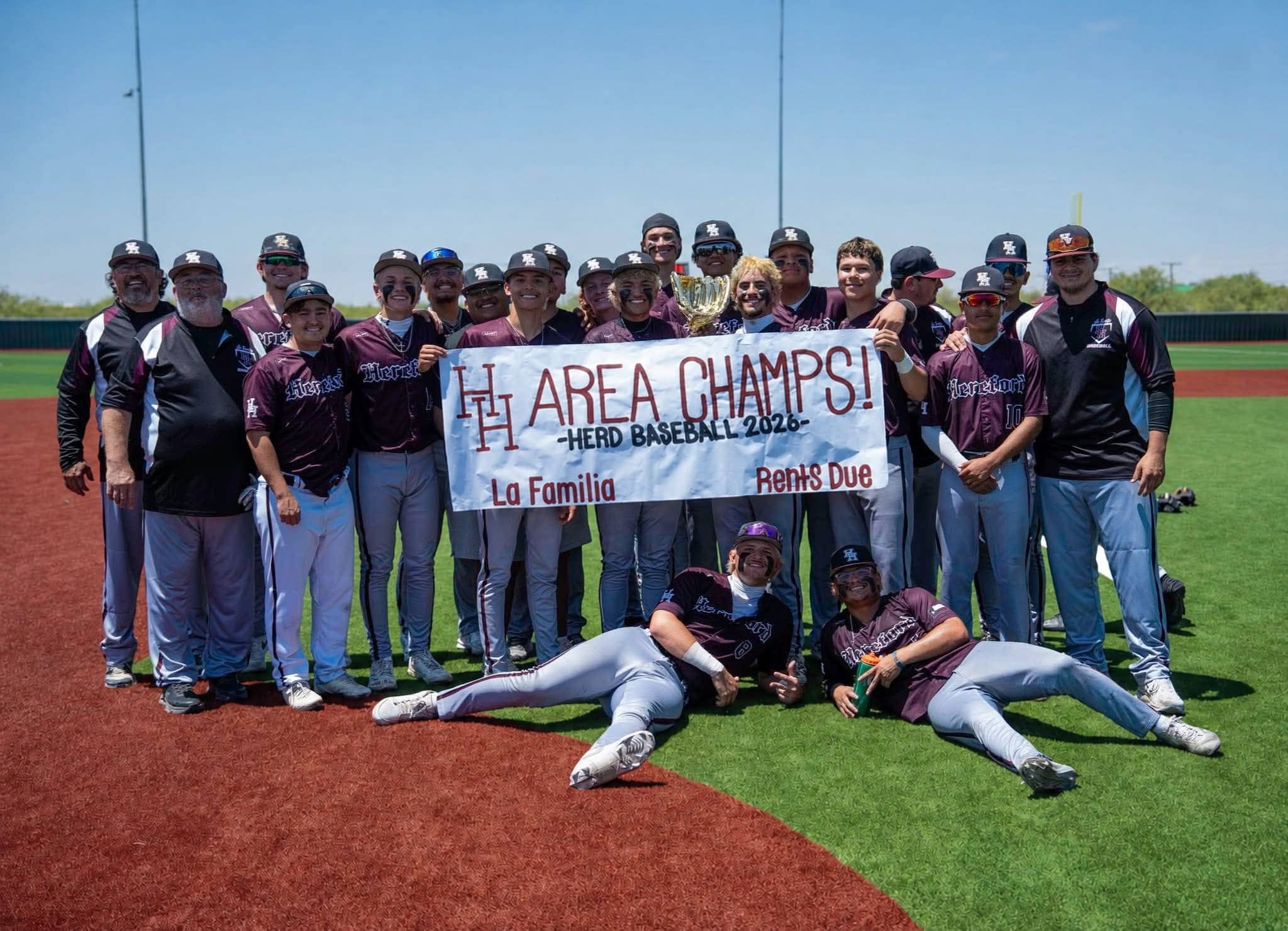 A baseball team crowd posing with a banner that reads 'We are champions' on a sunny field, celebrating a win with a trophy.