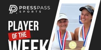 Two smiling young female athletes with medals display a large