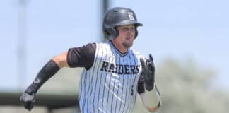 Baseball player in a white pinstripe uniform runs on the field, wearing a black batting helmet and gloves.