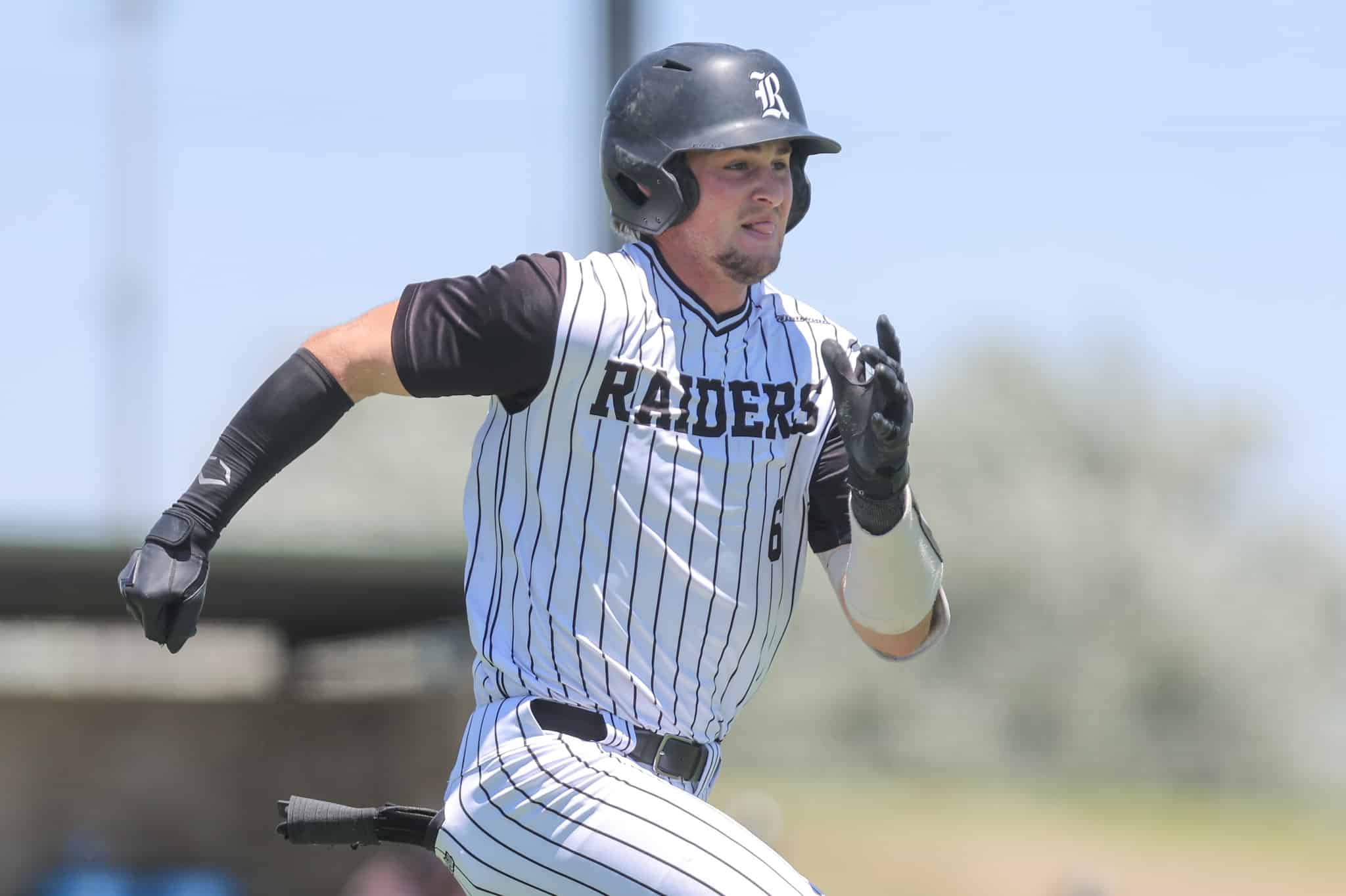 Baseball player in a white pinstripe uniform runs on the field, wearing a black batting helmet and gloves.