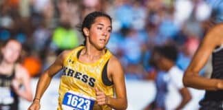 Female runner in a yellow patterned sleeveless top, bib 1623, mid-race with a crowd in the blurred background.