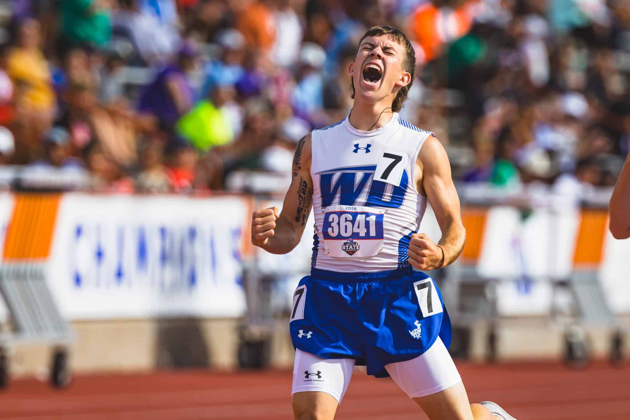 100A0846 | Press Pass Sports Male sprinter crosses the finish line, shouting in celebration, wearing white-blue uniform and bib 3641 on a track.