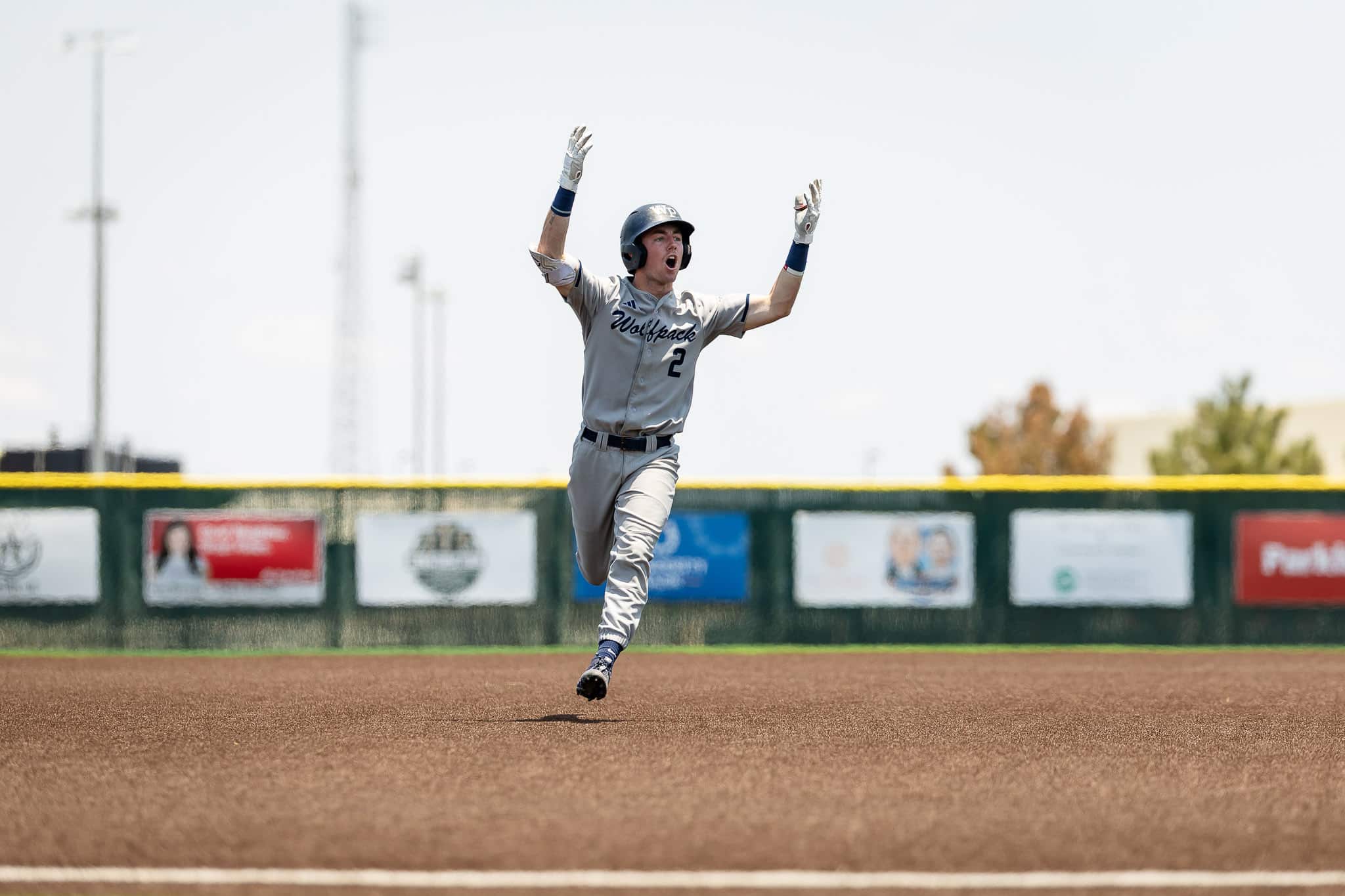 west-plains-baseball-jpegJoe-pps-1 | Press Pass Sports Baseball player in gray uniform with number 2 raises both arms in celebration on the infield dirt, helmet on.
