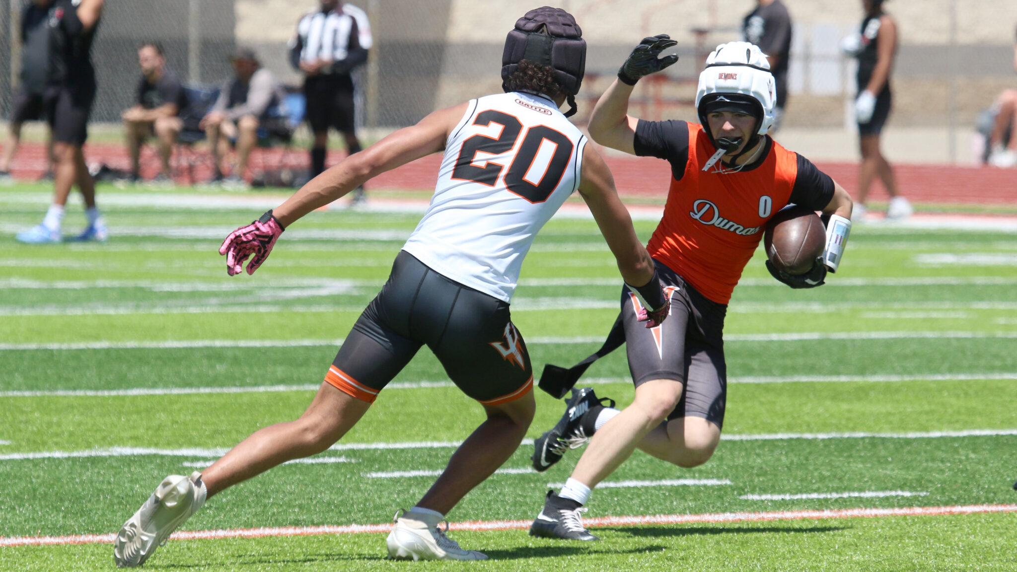 0 - Dumas - 7-on-7 - 053026 | Press Pass Sports Lacrosse players sprint toward the ball on a sunny field; white jersey #20 defends against an orange-clad attacker with the ball.