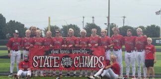 New Home Leopards baseball team posing on the field with a 'State Champs' banner.