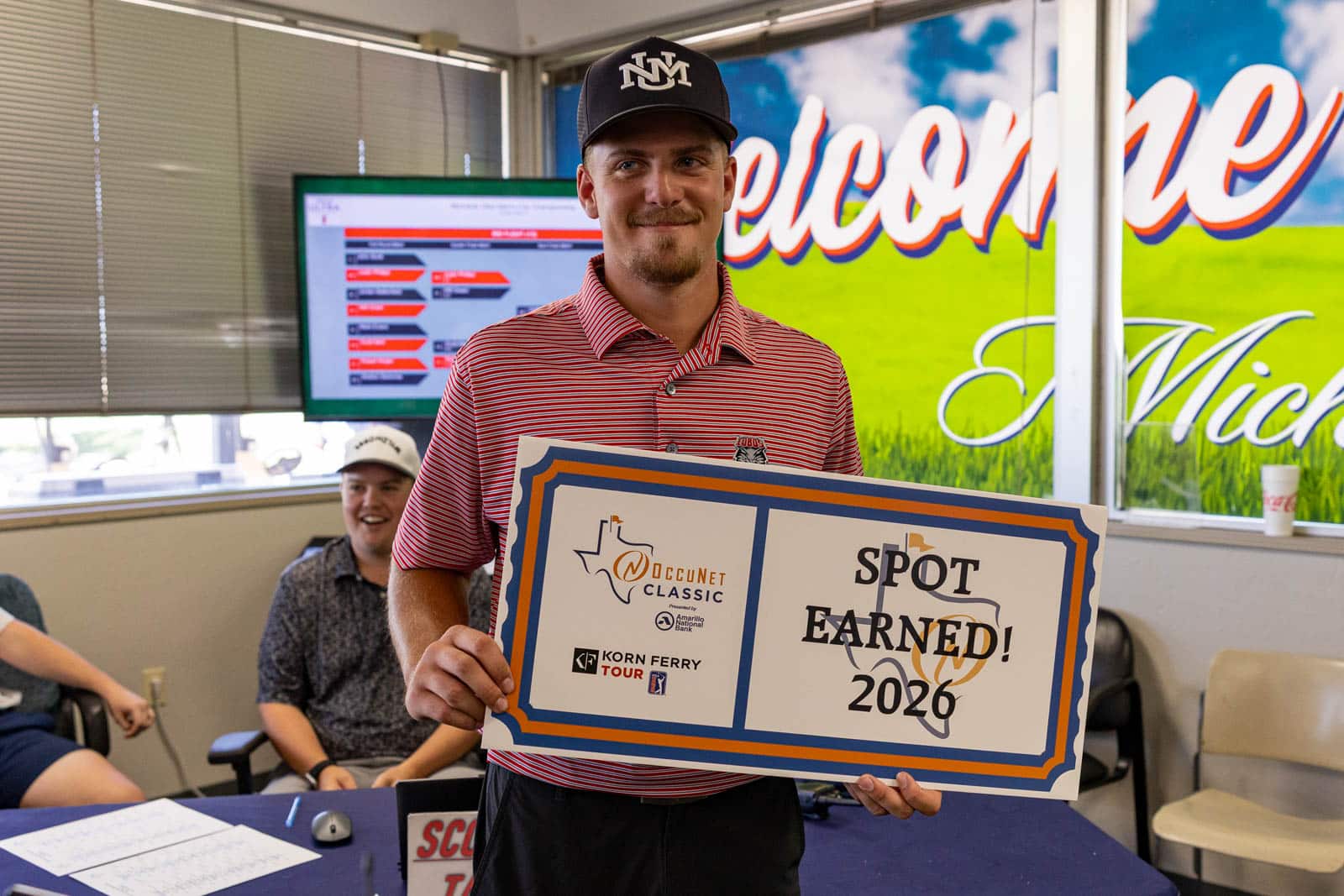 MUMCC-76 | Press Pass Sports Smiling man in a red striped polo holds a large'Spot Earned! 2020' certificate with logos at an indoor award event.