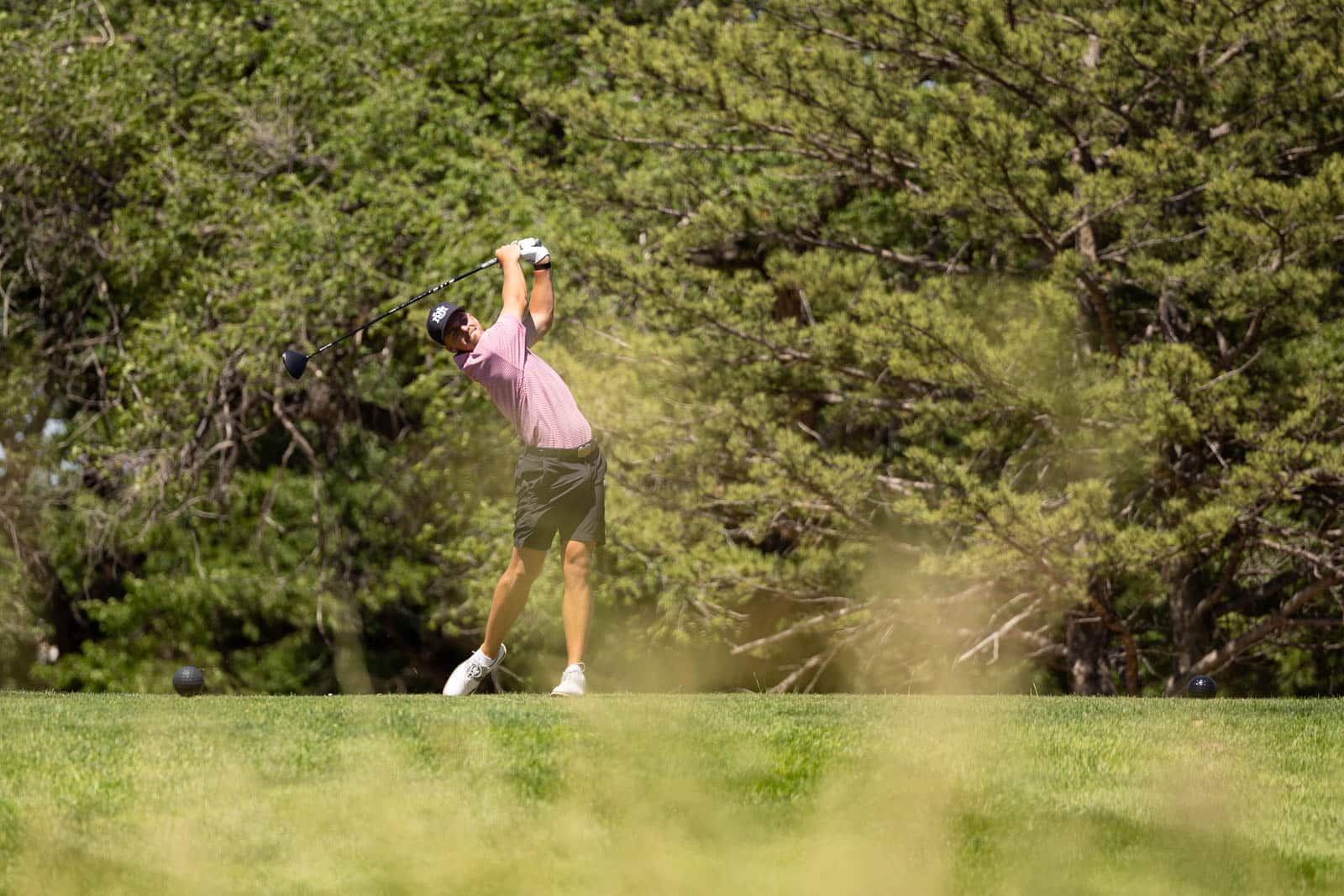 MUMCC-57 | Press Pass Sports Golfer mid-swing on a grassy tee with a wooded backdrop, wearing a pink shirt and cap