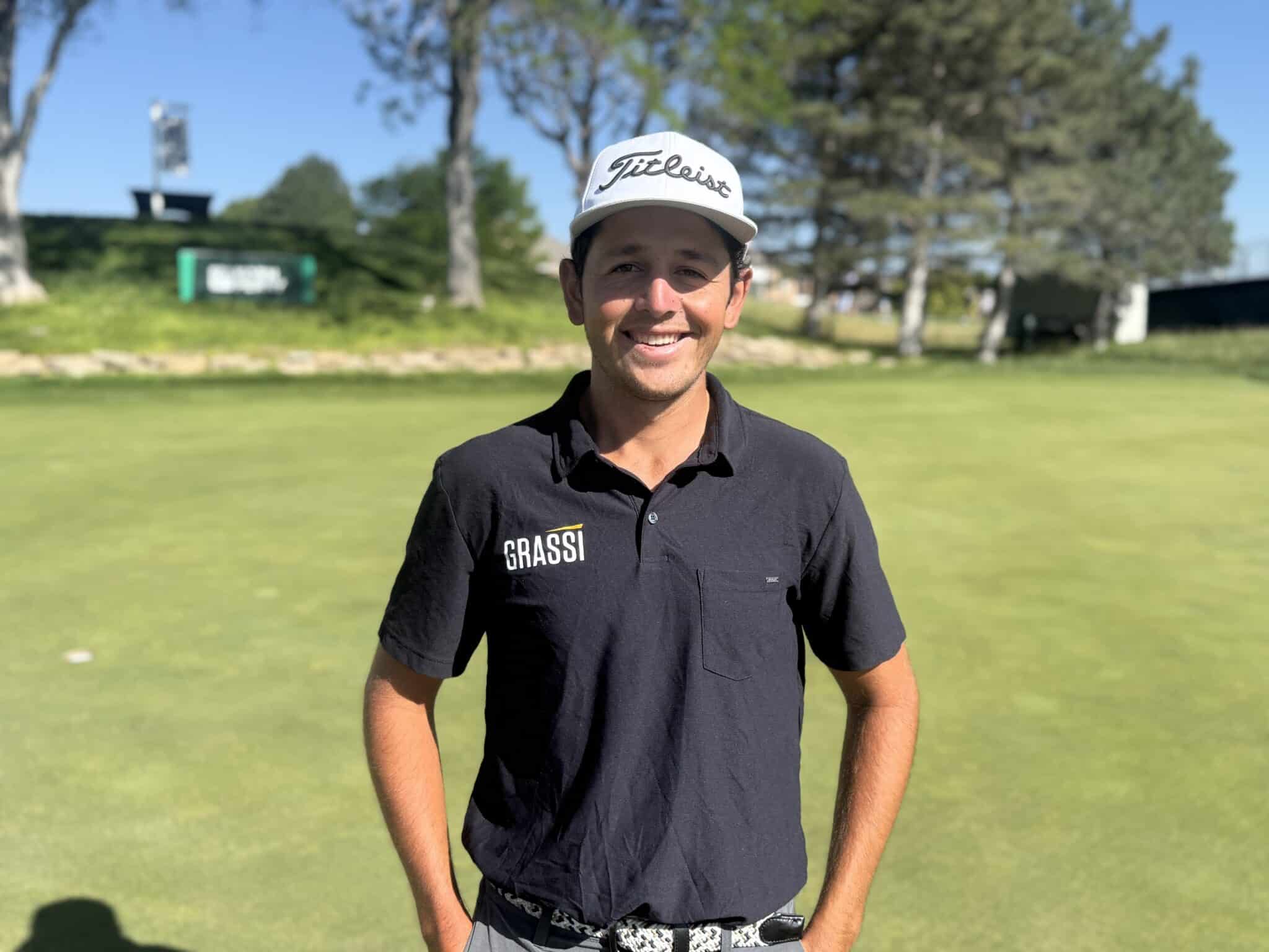 IMG_5345 | Press Pass Sports Smiling man in a black polo shirt and white Titleist cap on a sunny golf course.