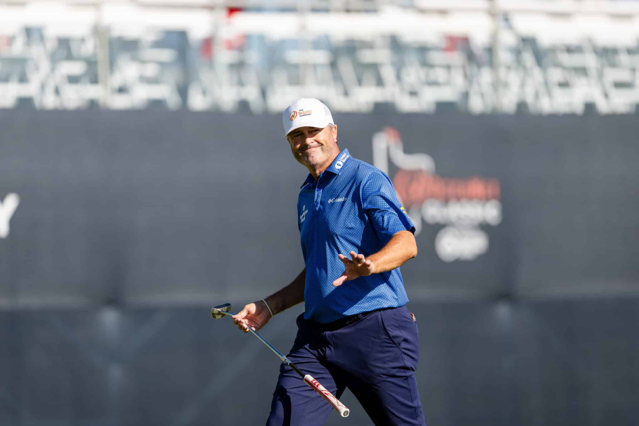 Korn Ferry Occunet Classic Day 1 | Press Pass Sports Male golfer in a blue polo on a golf course, smiling while holding a putter.