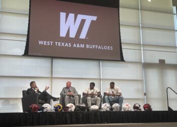 IMG_4305 | Press Pass Sports Panel discussion on a stage with four men in suits; football helmets lined up at the edge, WTAM Buffaloes logo on screen behind