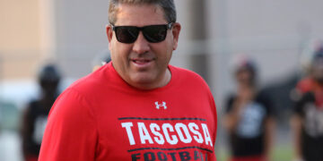 Man wearing a red Tascosa Football shirt and dark sunglasses, outdoors during daytime.