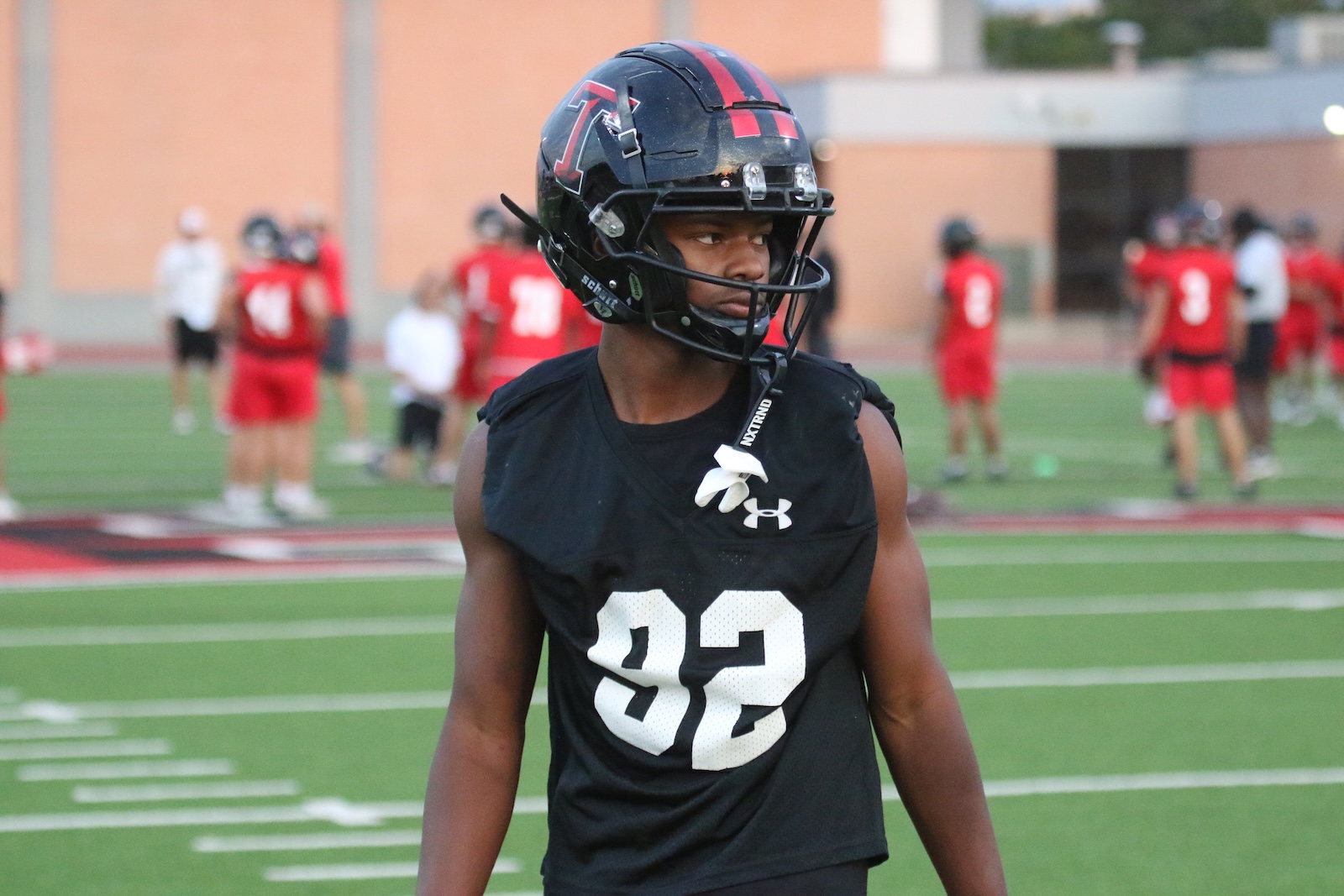 Young football player wearing a black jersey with the number 32 and a helmet on a practice field.