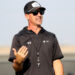 1K6A8179 | Press Pass Sports Man wearing a black athletic shirt, cap, and sunglasses speaks outdoors, gesturing with his left hand.