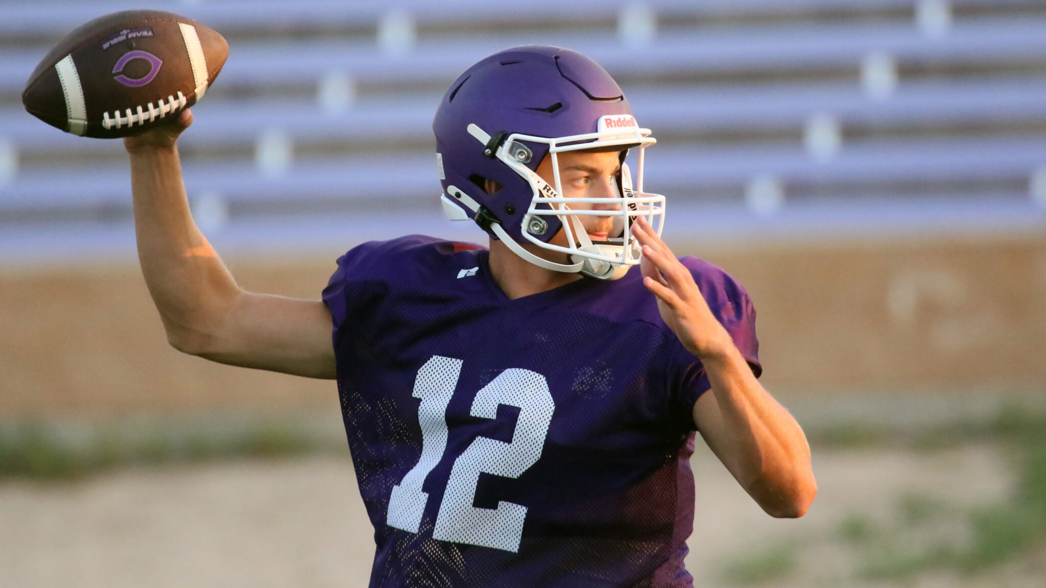 1K6A8554 | Press Pass Sports Young football quarterback in purple jersey throwing a ball during practice on a field.