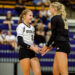 bushland-vs-canyon-volleyball-2026-jpegJoe-9 | Press Pass Sports Two volleyball players share a high-five on the court after a point; white jersey number 2 and black jersey number 10, with fans in bleachers behind them.