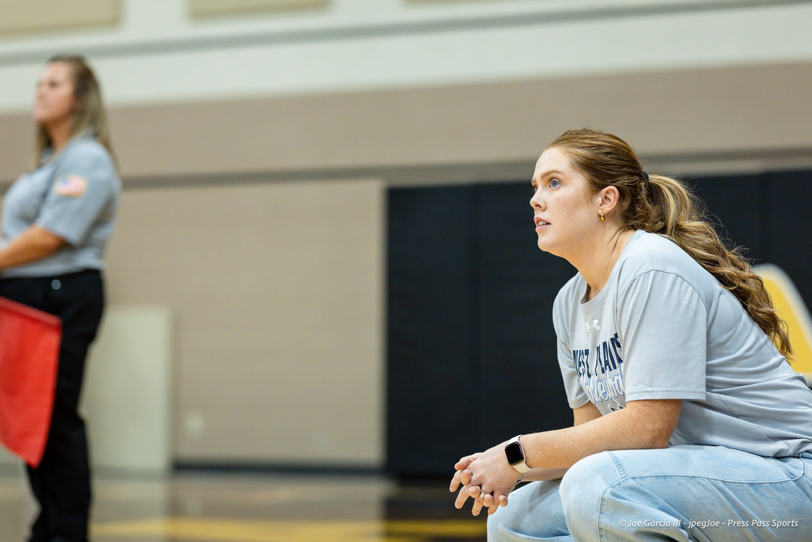 west-plains-vs-amarillo-high-2026-jpegJoe-pps-3 | Press Pass Sports Athlete in a light blue shirt kneels in a gym, focused on something off-camera, with a blurred person in the background.