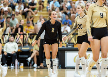 west-plains-vs-amarillo-high-2026-jpegJoe-pps-9 | Press Pass Sports Volleyball players on the court celebrate; a player in black with number 2 smiles as teammates in beige jerseys (numbers 20 and 9) stand nearby, cheering crowd in the stands behind.