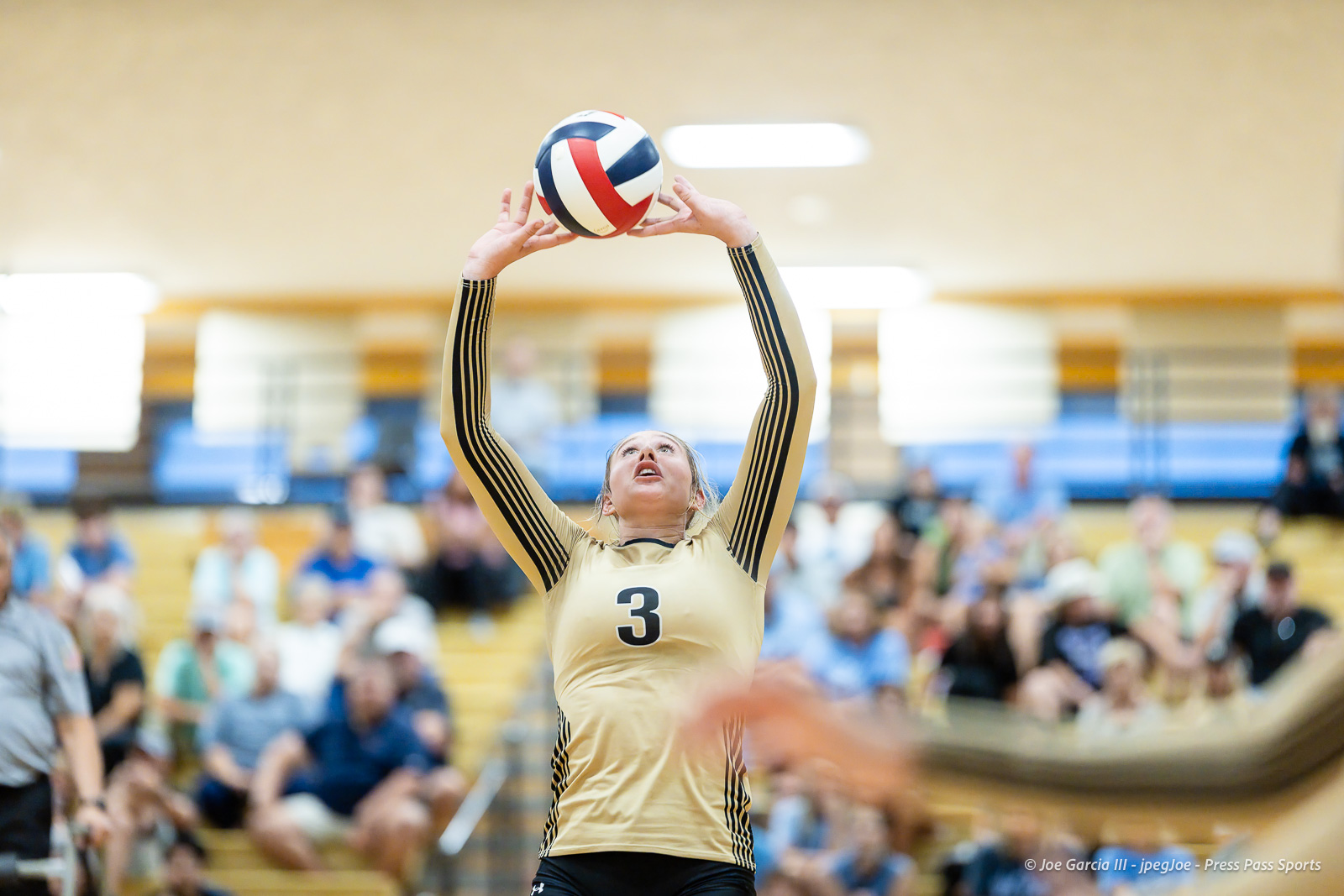 west-plains-vs-amarillo-high-2026-jpegJoe-pps-15 | Press Pass Sports Volleyball player in a gold jersey with number 3 raises arms to set a multicolored ball in a gym crowded with spectators.