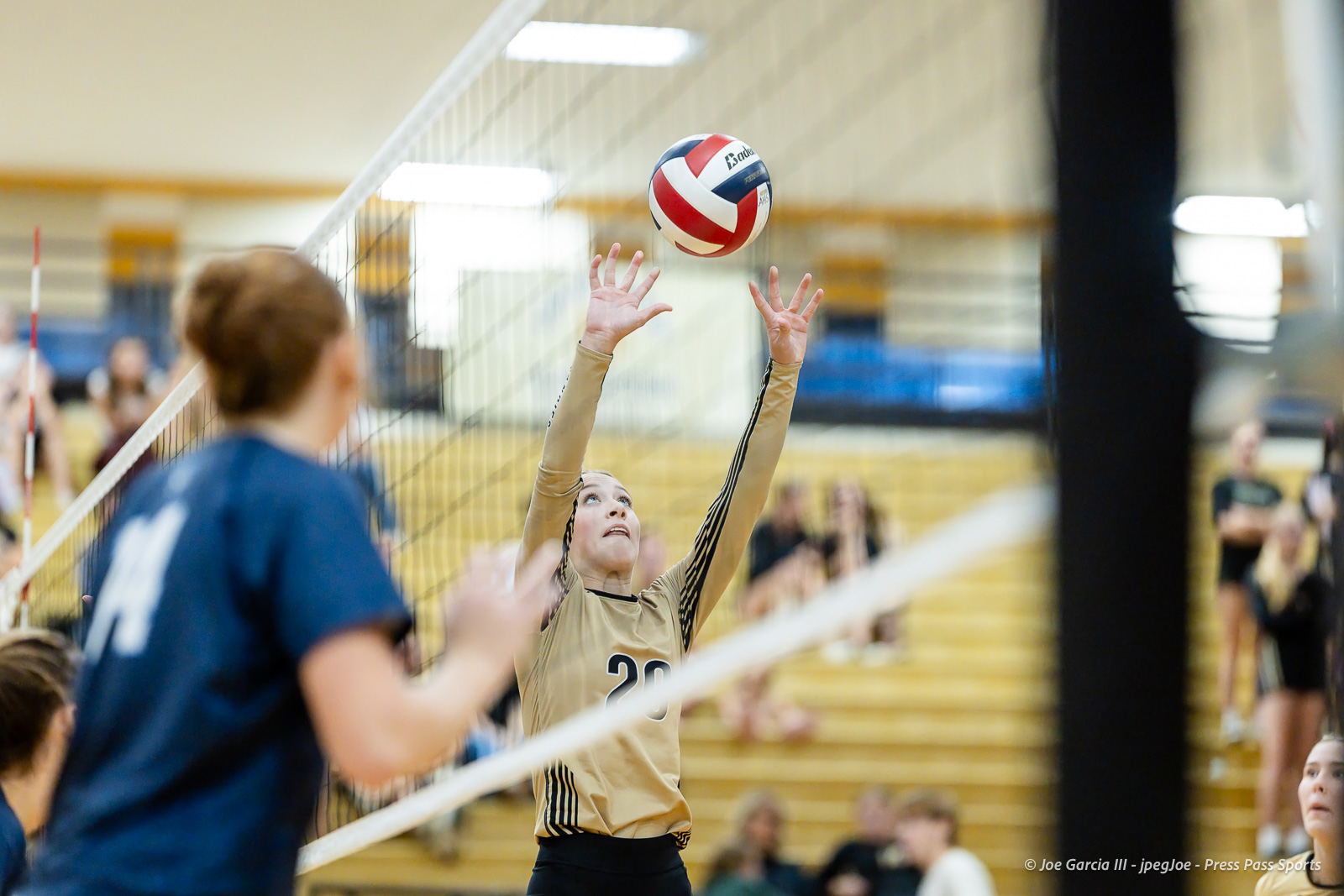 west-plains-vs-amarillo-high-2026-jpegJoe-pps-24 | Press Pass Sports Player in beige uniform rises to set or block the volleyball at the net during a match in a gymnasium.