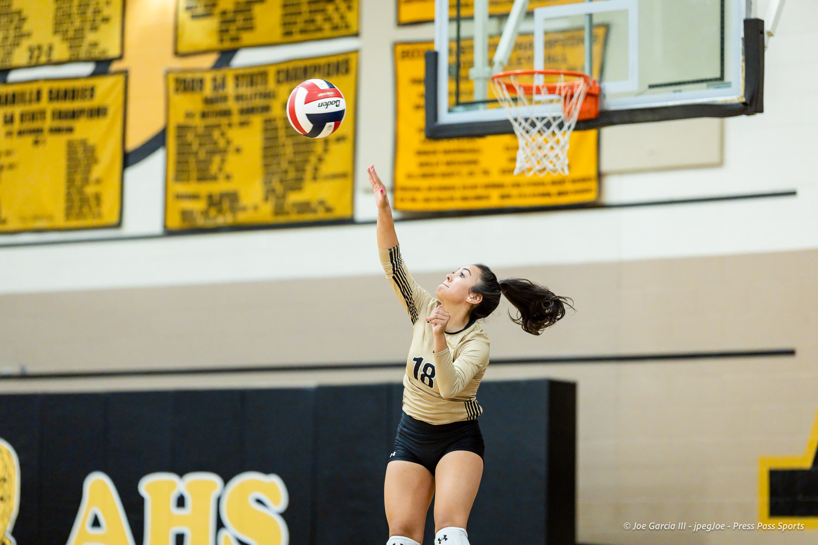 west-plains-vs-amarillo-high-2026-jpegJoe-pps-25 | Press Pass Sports Female volleyball player in a beige jersey number 18 reaches to hit a ball during a gym match with yellow banners in the background.