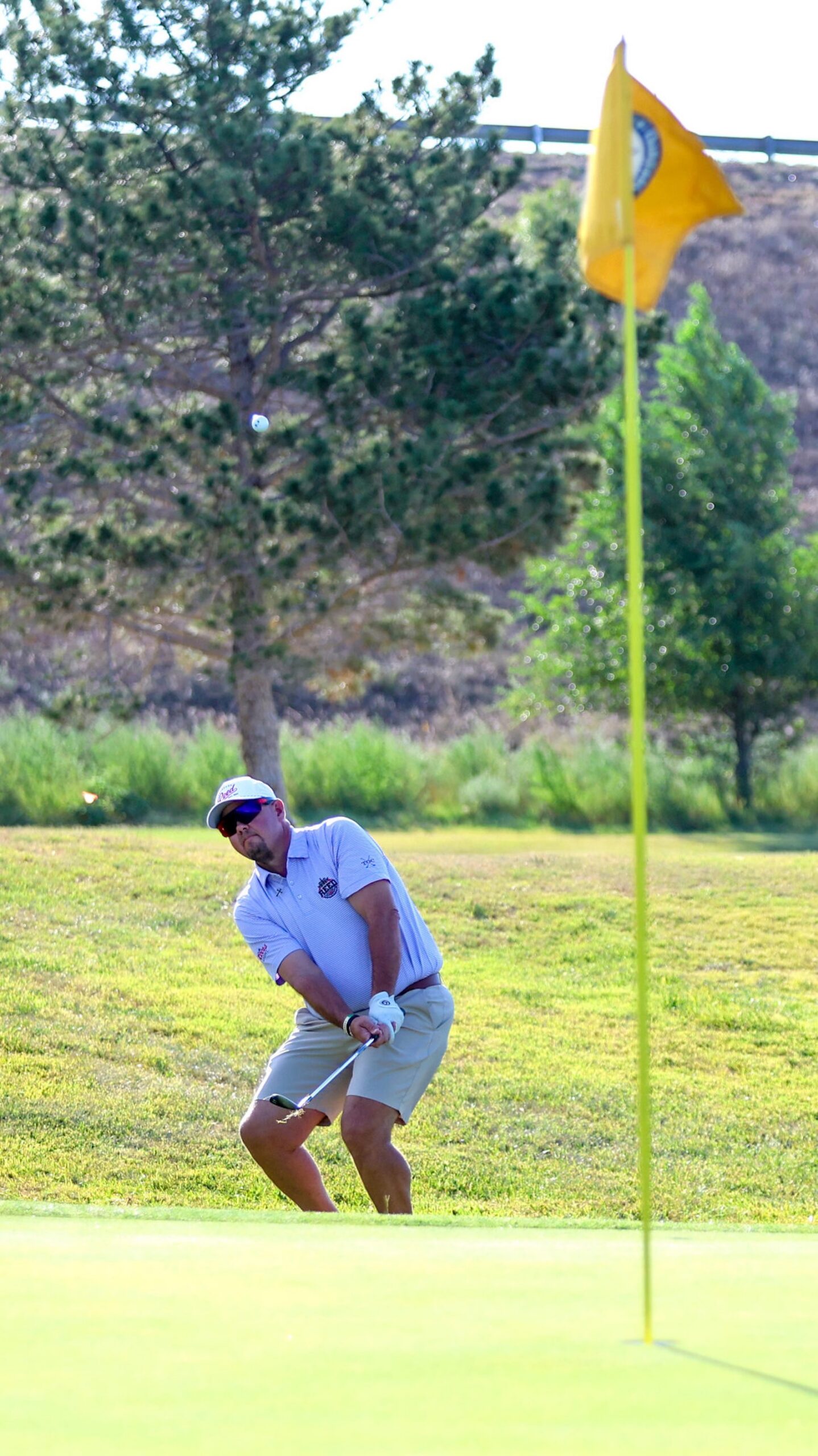 20260814-CoorsTOC-Day2-019 | Press Pass Sports Male golfer in a white polo and cap backswing near a yellow flag on a sunny golf course