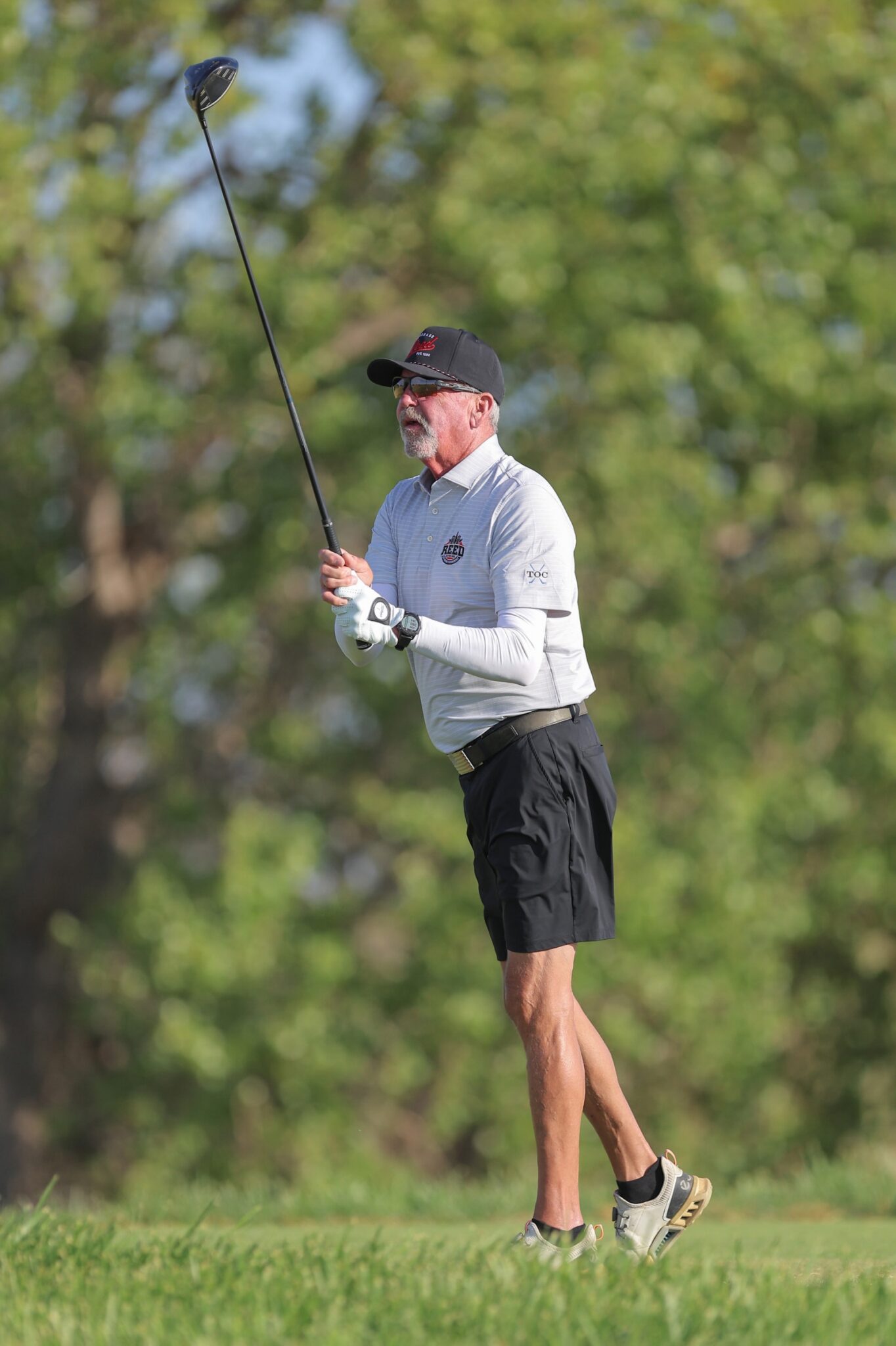 20260815-CoorsTOC-Day3-018 | Press Pass Sports Older man in a light polo and cap mid-swing with a golf club on a sunny golf course