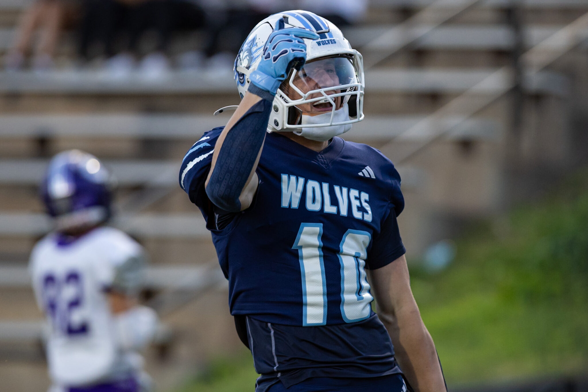 CHS-WPHS-FB-9 1 | Press Pass Sports Football player in a blue Wolves jersey raises his helmet in celebration on the field.