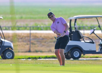 20260815-CoorsTOC-Day3-044 | Press Pass Sports Golfer in a pink polo swinging a club on a sunny golf course with carts in the background, ball in the air