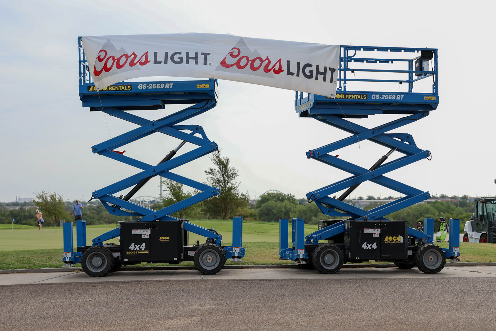 CoorTOC_FinalDay-3 | Press Pass Sports Two blue scissor lifts raising a large Coors Light banner between them outdoors.