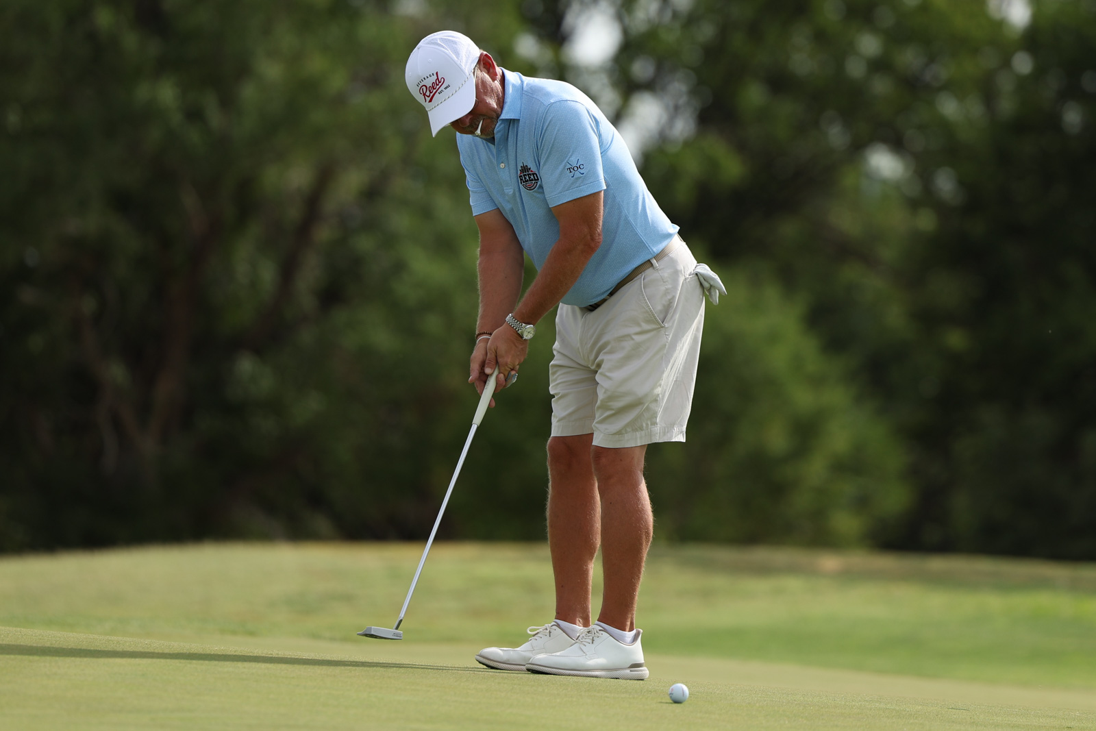 CoorTOC_FinalDay-12 | Press Pass Sports Male golfer in a light blue polo and khaki shorts preparing a putt on a well-manicured green.