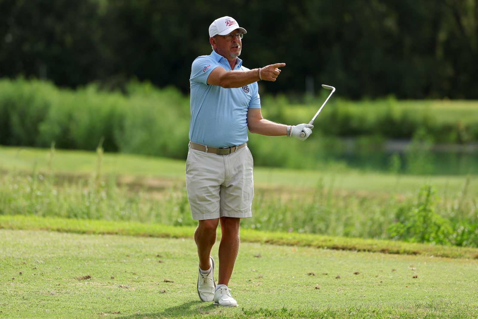 CoorTOC_FinalDay-18 | Press Pass Sports Older man in a light blue polo and beige shorts points with a golf club on a sunny course.