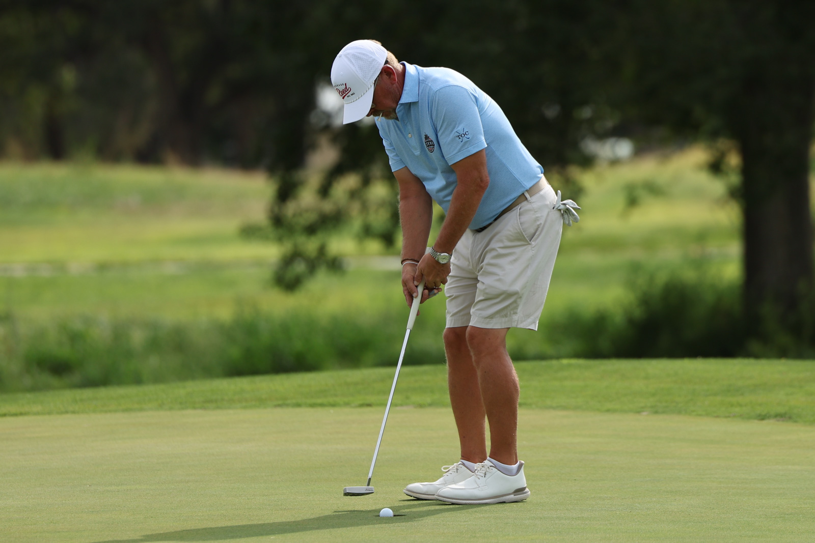 CoorTOC_FinalDay-23 | Press Pass Sports Golfer in a light blue polo and white cap lining up a putt on a green golf course.