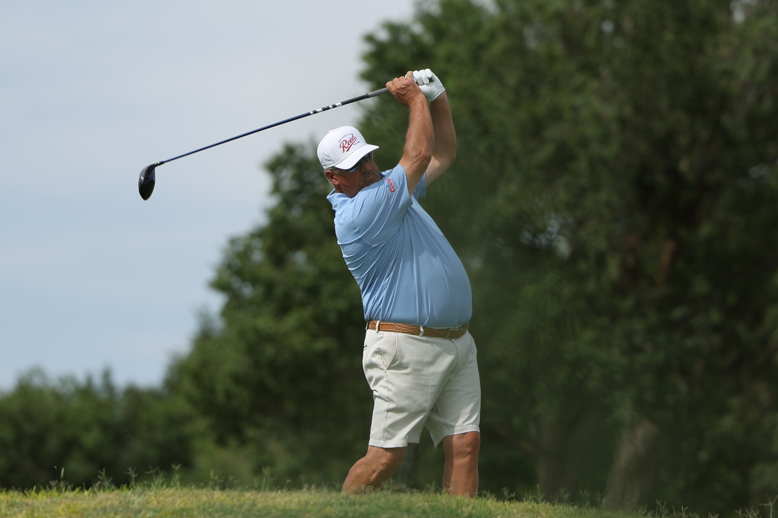 CoorTOC_FinalDay-37 | Press Pass Sports Male golfer in a light blue polo and white cap mid-swing on a sunny golf course.