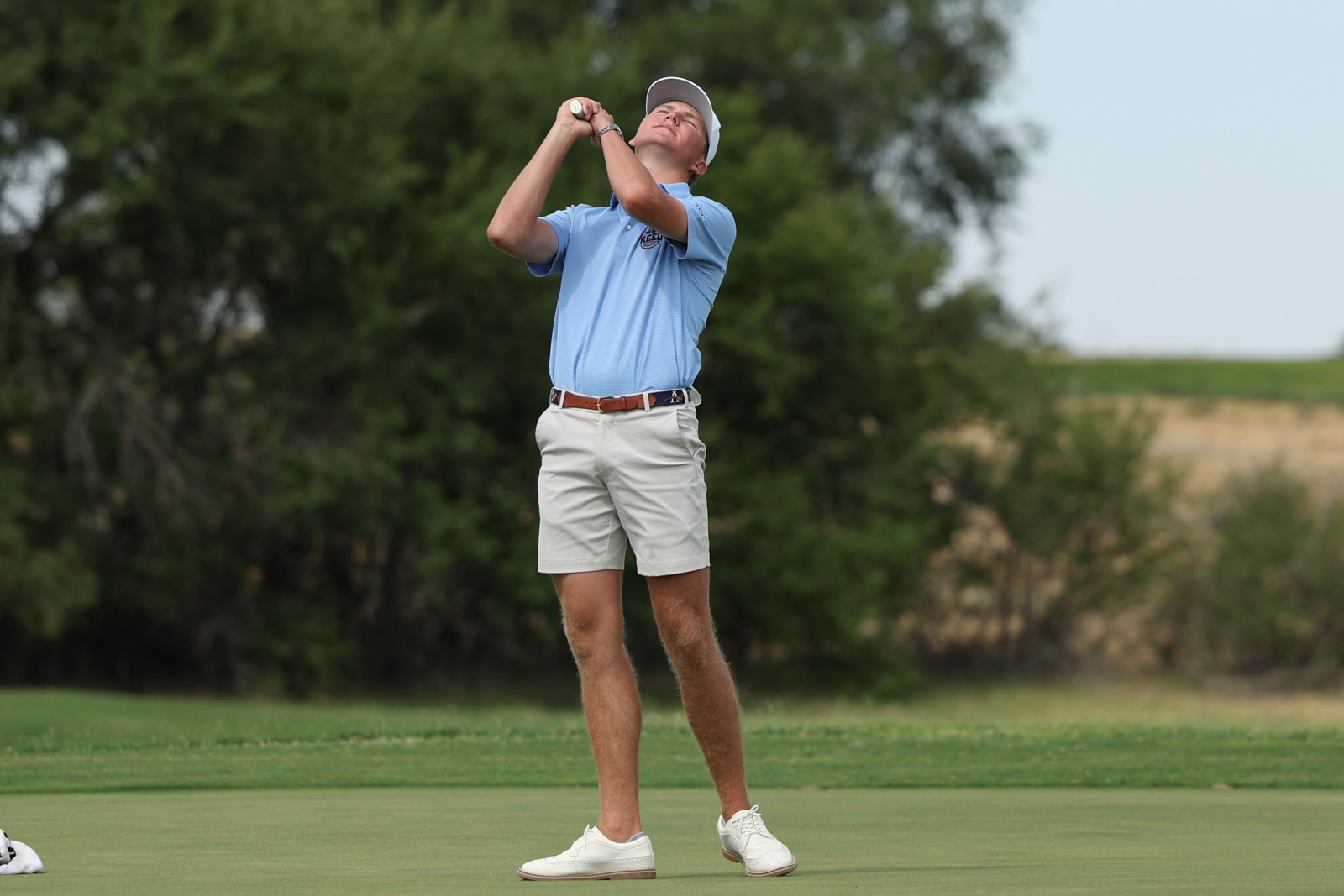 CoorTOC_FinalDay-41 | Press Pass Sports Golfer in light blue polo and white shorts follows through on a backswing on the green golf course surface.