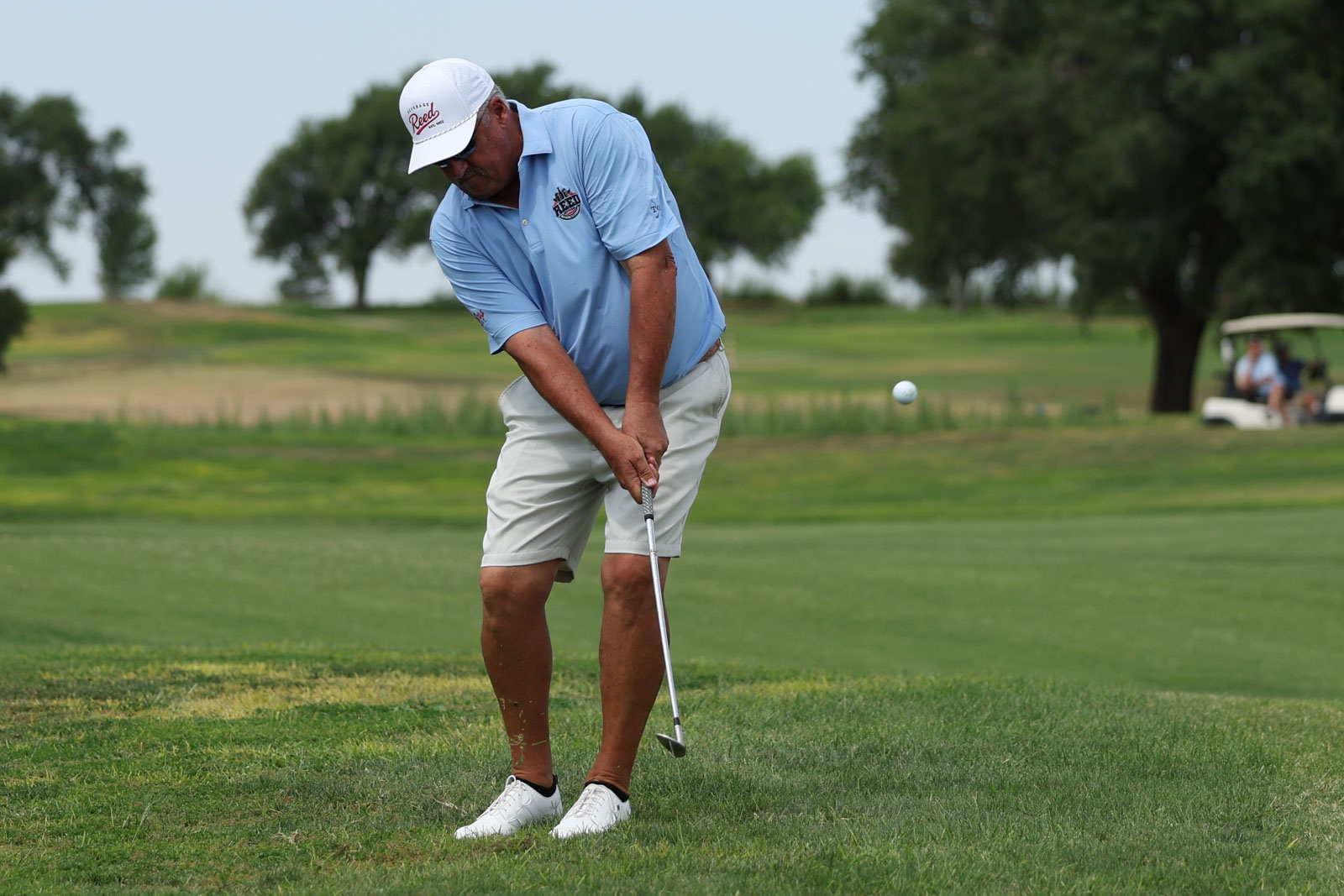 CoorTOC_FinalDay-43 | Press Pass Sports Golfer in a light blue polo and white cap mid-swing on a green golf course.