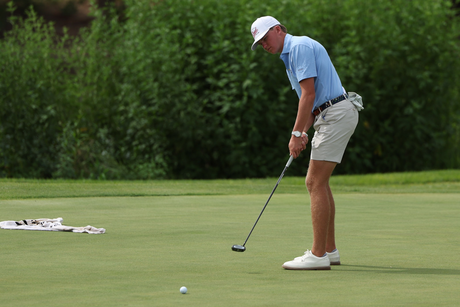 CoorTOC_FinalDay-44 | Press Pass Sports Golfer wearing a light blue polo and white cap lining up a putt on the putting green.