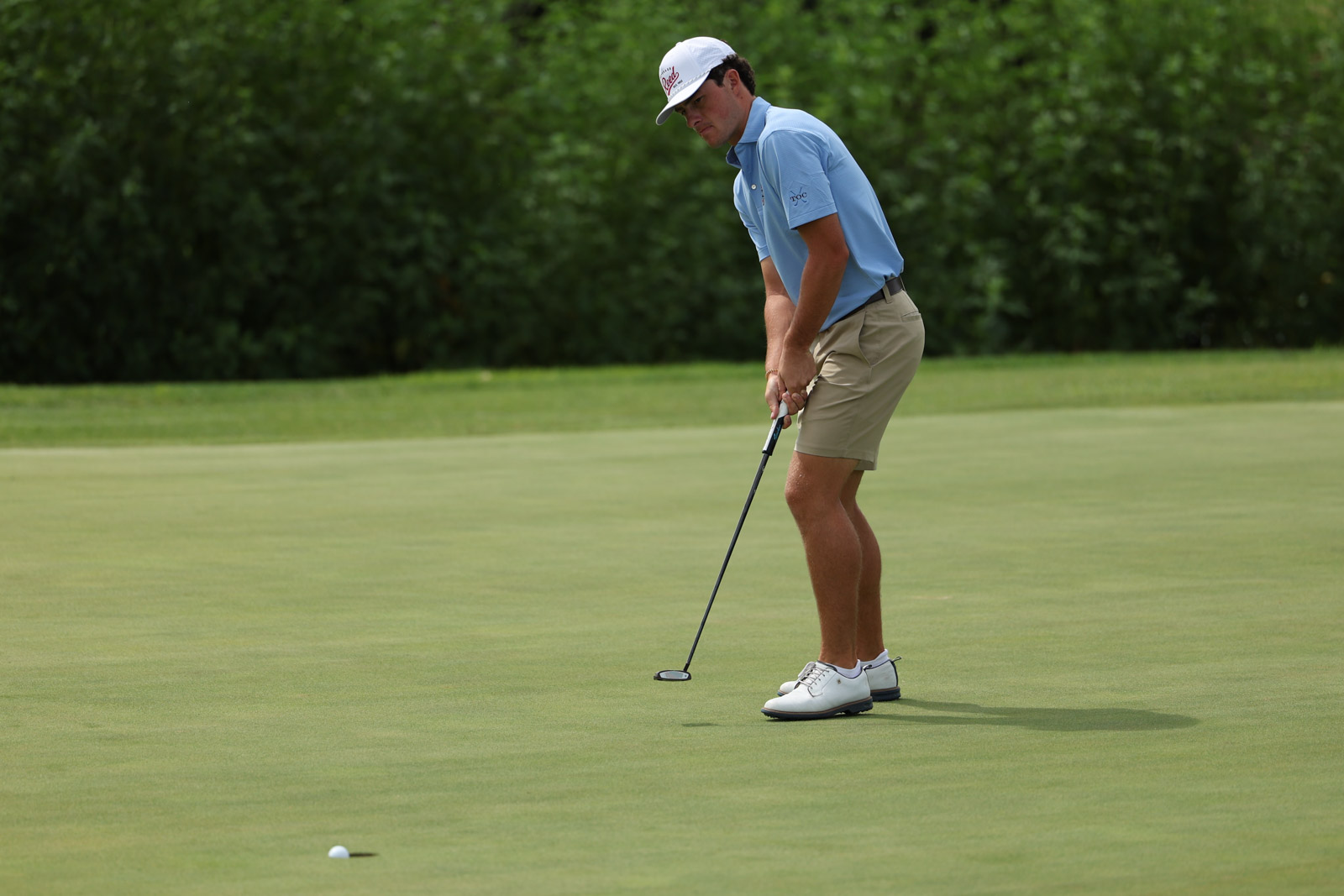 CoorTOC_FinalDay-45 | Press Pass Sports Golfer in a light blue polo and khaki shorts lining up a putt on a green.