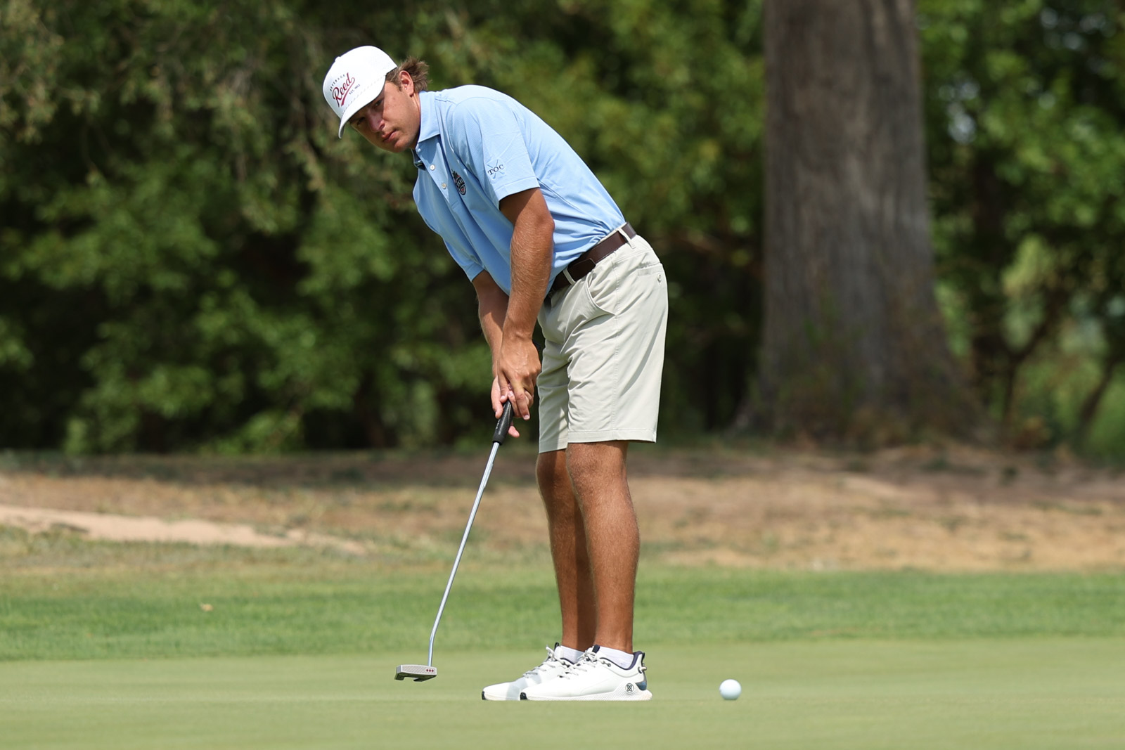 CoorTOC_FinalDay-52 | Press Pass Sports Golfer in a light blue polo and beige shorts lining up a putt on the green.