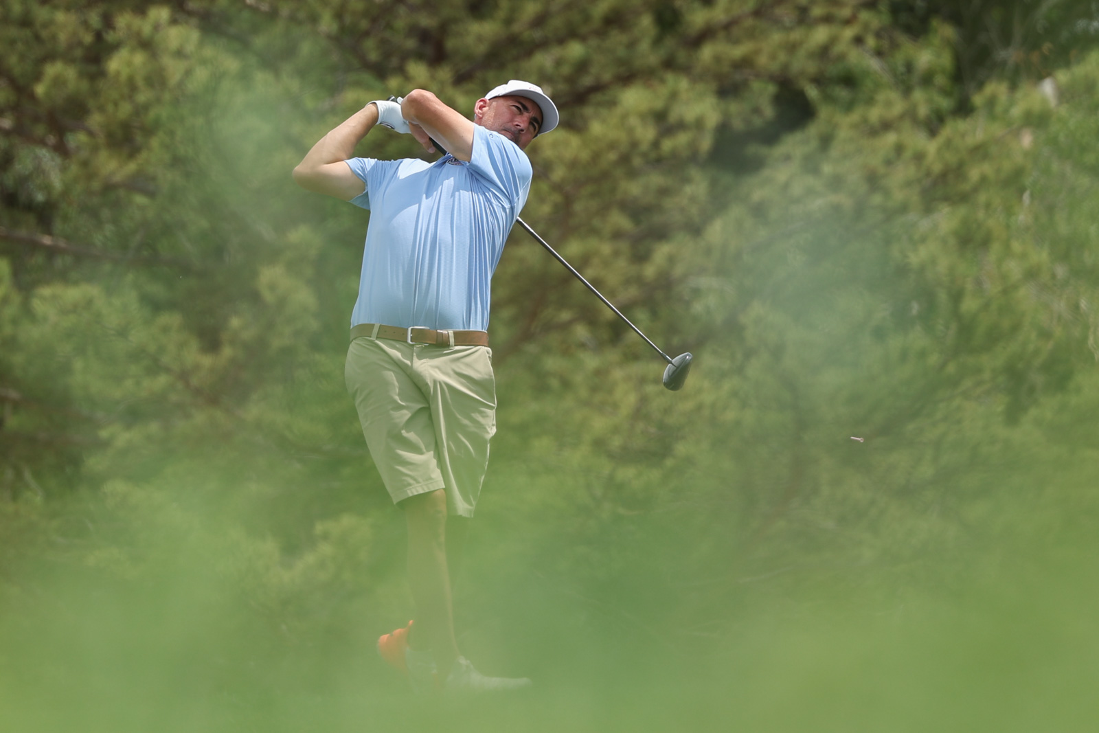 CoorTOC_FinalDay-54 | Press Pass Sports A man in a light blue polo shirt and beige shorts mid-swing with a golf club on a lush golf course.