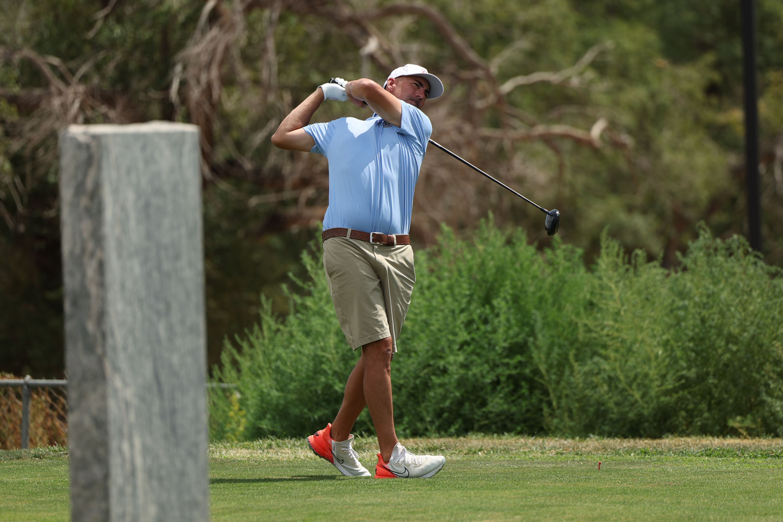 CoorTOC_FinalDay-60 | Press Pass Sports A man in a light blue polo and khaki shorts swings a golf club on a sunny course, mid‑back swing.