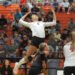 20260818-Tascosa-Caprock-VB-005 | Press Pass Sports Female volleyball player in a white jersey number 1 leaps upward to spike, with a crowded orange gym audience in the background.