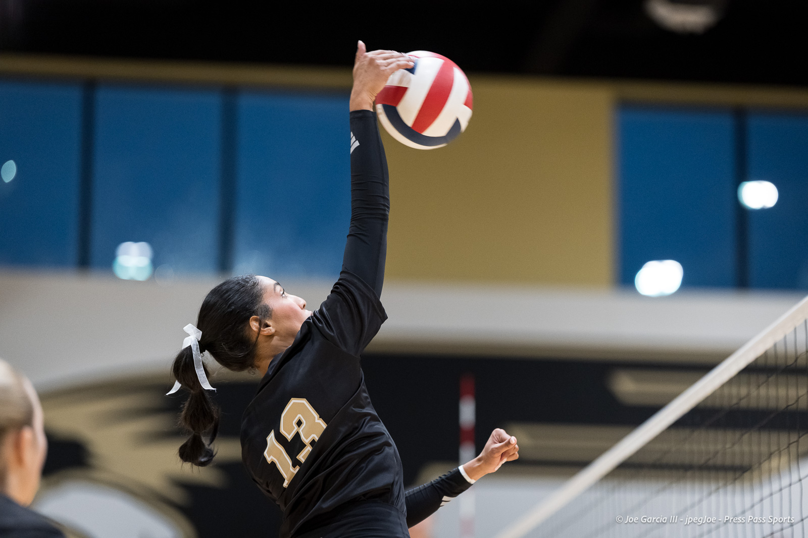 Female volleyball player in a black uniform leaps to spike the ball inside a gym.](not relevant)