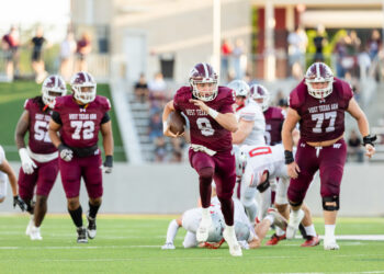 western-colorado-vs-wtamu-jpegJoe-pps-12 | Press Pass Sports West Texas A&M quarterback #9 runs with the ball as teammates block near a sunny football field.
