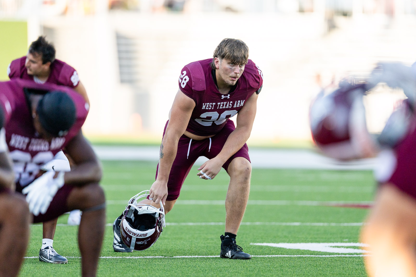 western-colorado-vs-wtamu-jpegJoe-pps-2 | Press Pass Sports West Texas A&M football player #38 crouches in a drill, helmet in hand on a green turf field.