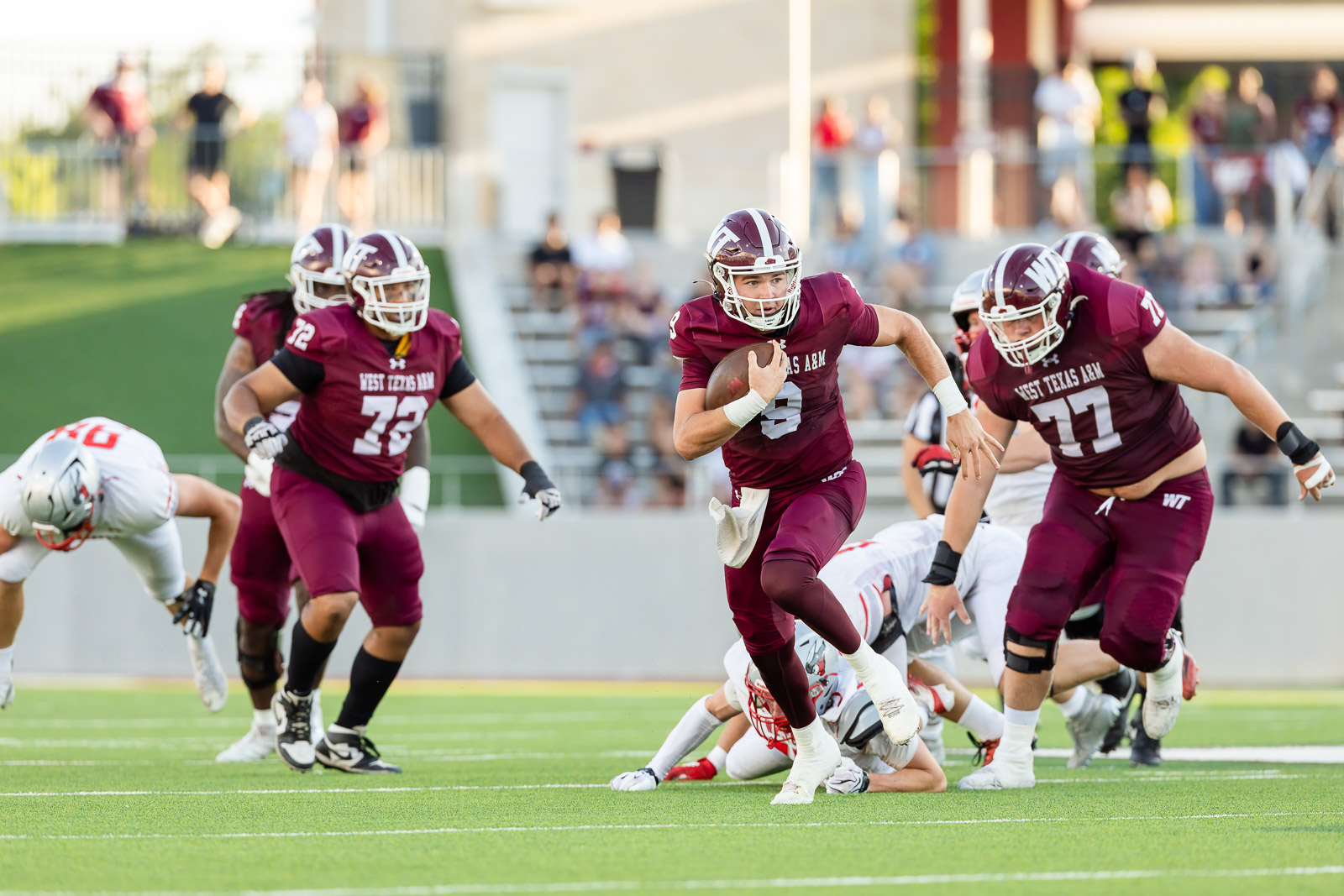 western-colorado-vs-wtamu-jpegJoe-pps-11 | Press Pass Sports West Texas A&M running back in maroon jersey carries the ball as teammates block downfield on a football field.